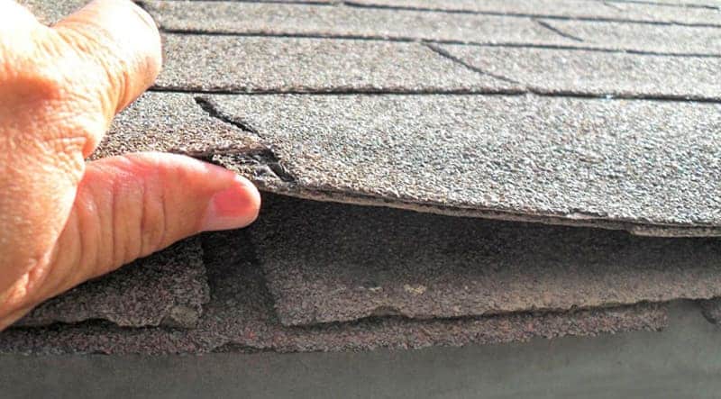 A close view of a hand inspecting a panel of the roof of house