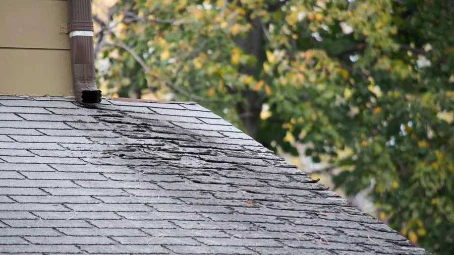 A view of a brick house roof leaking with a water drain pipe over it