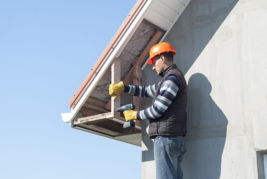 A view of a constructor drilling the soffit and fascia of roof