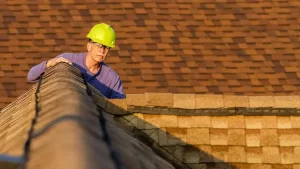 A view of a contractor wearing a hat inspecting a roof