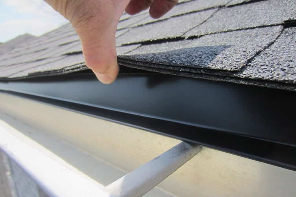 A view of a hand inspecting a drip edge on a roof