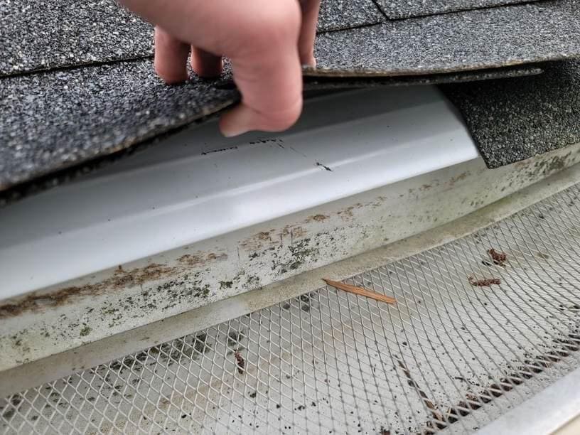 A view of a person examining an old roof edge