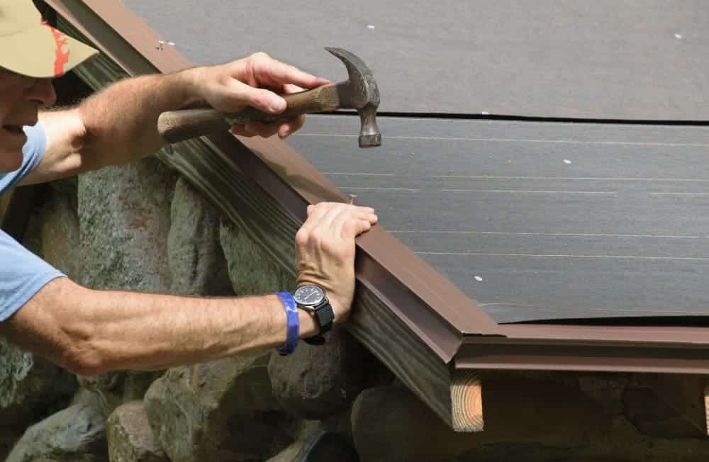 A view of a person hammering a nail into a roof edge