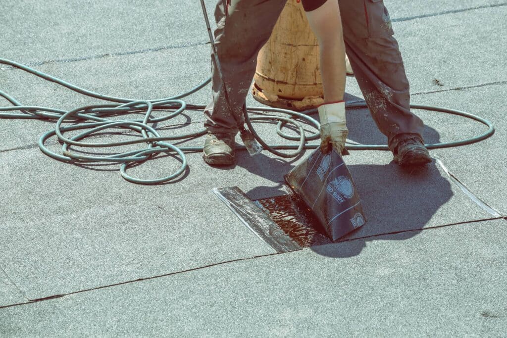 A view of a person using a tool to stick the rolling paper for roofing