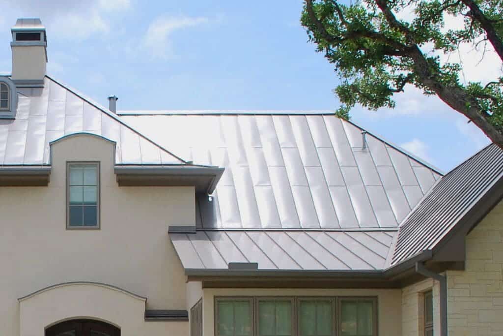 A view of a steel metal roofing house with a tree on the side