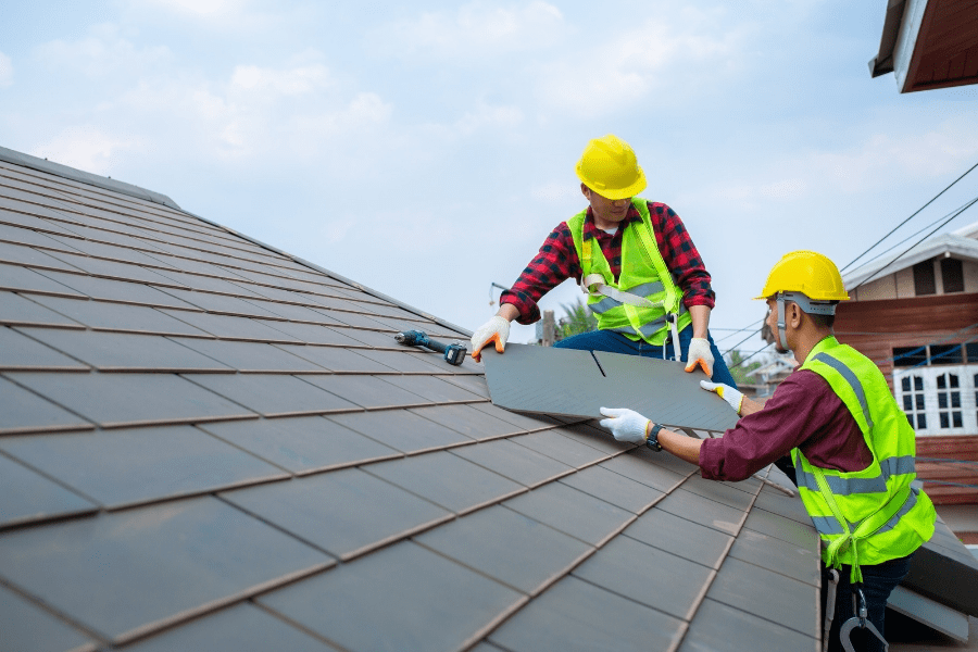 A view of two contruction workers installing roofing over a house