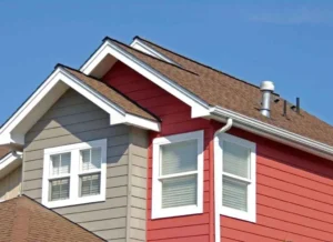 A view of a red and brown house white windows and a roof eave style