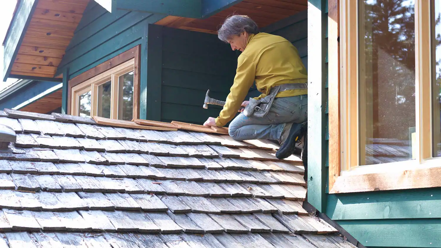 a contractor repairing a roof with hammer