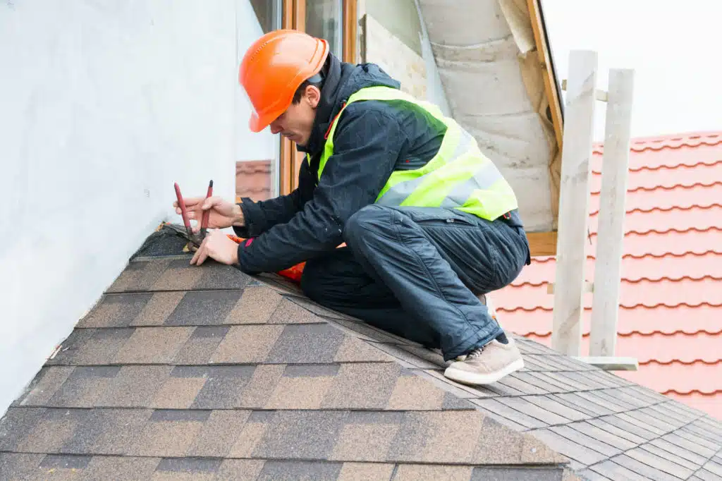 Roofer builder worker dismantling roof shingles