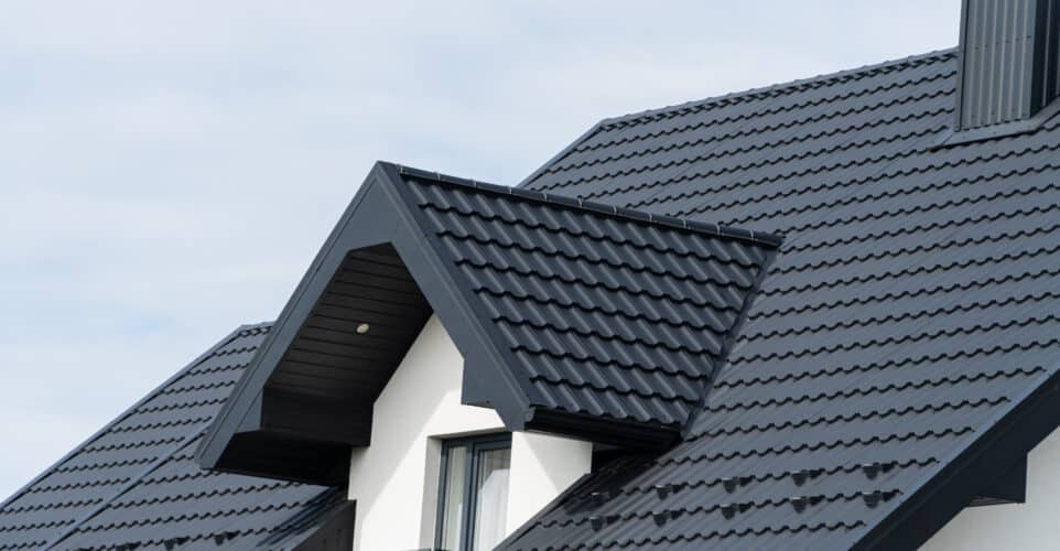 A beautiful modern house is covered with black metal tiles Roofing of metal profile wavy shape