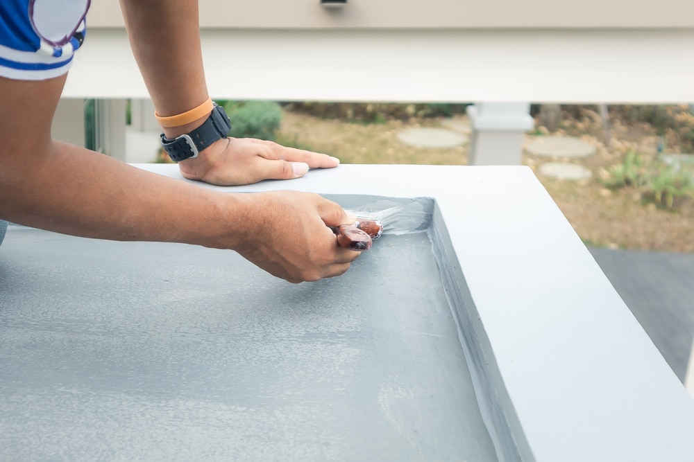 zoomed view of male hands painting a roof deck