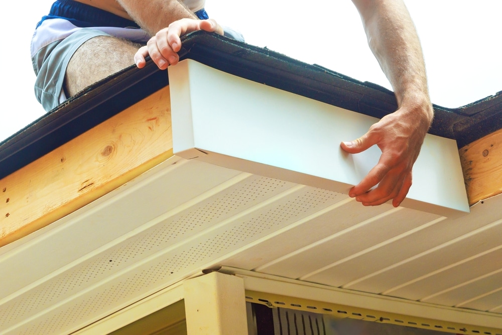 a person's hand installing aluminum composite panel fascia trim at wood corner frame of an exterior wooden to protect against wood damage