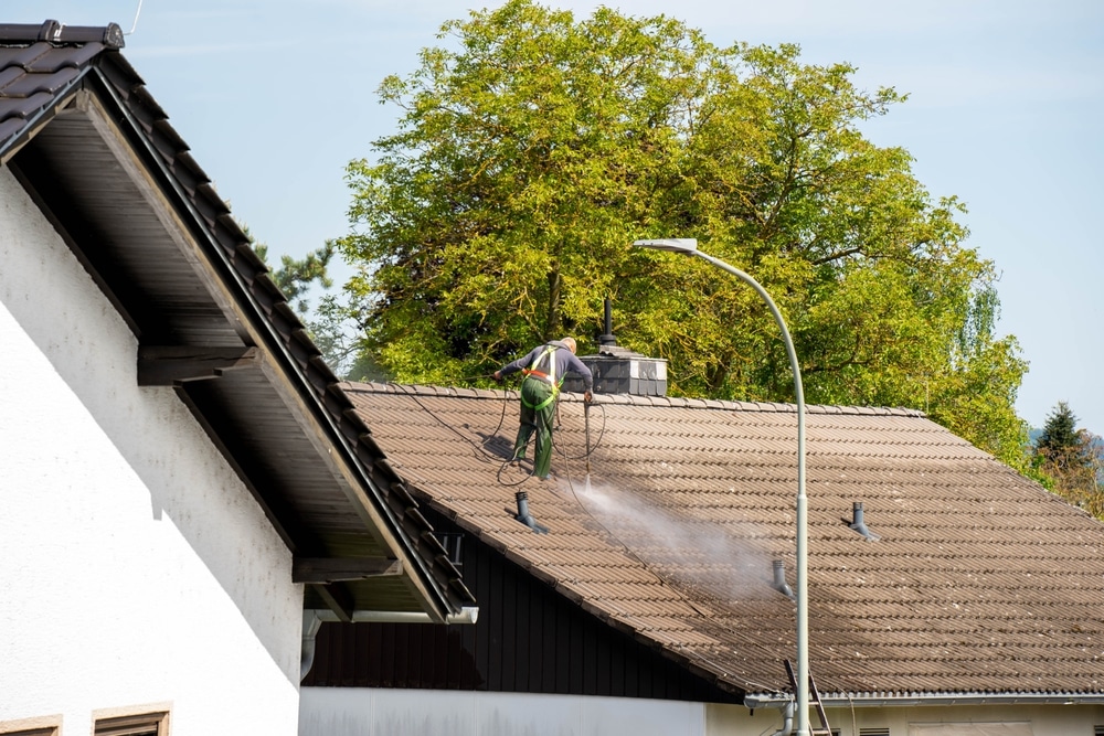 a person cleaning roof with pressure of water