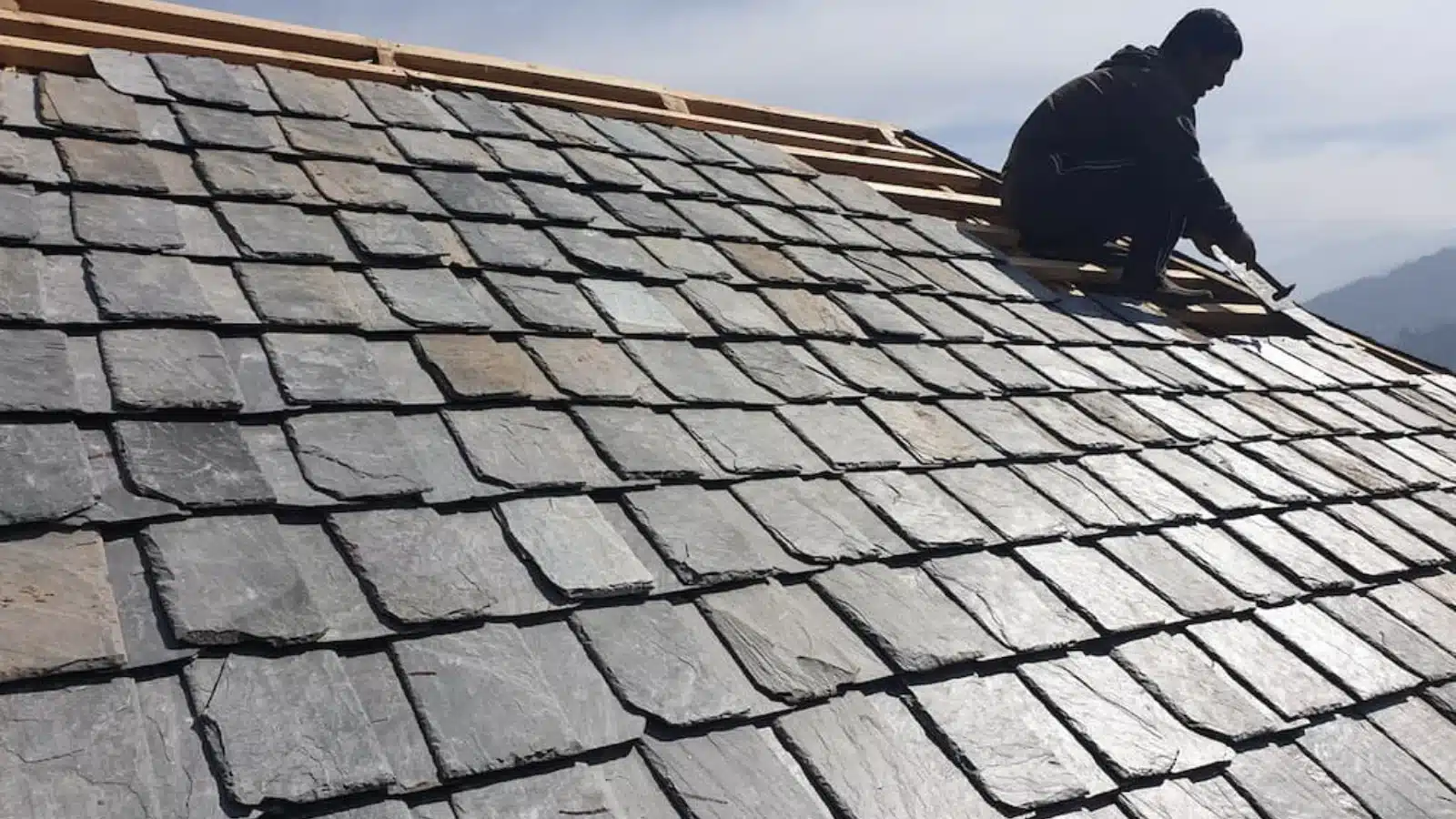 view of a person fixing slate roofs