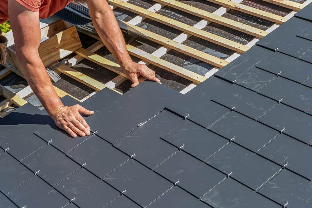 close up of male hands working on installing slate tiles close up of male hands working on installing slate tiles