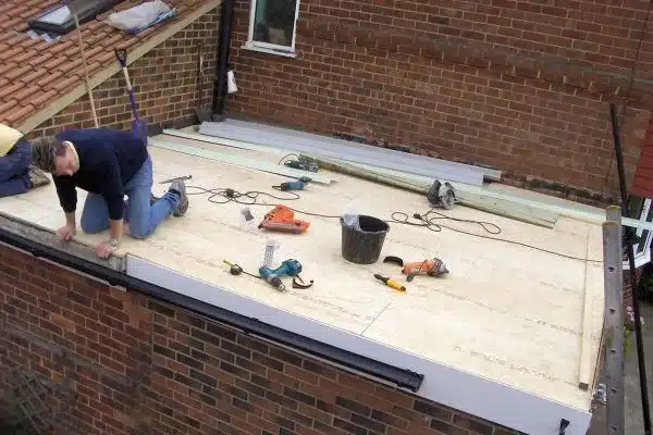 a roofer installing fibreglass roofing layer a roofer installing fibreglass roof layer
