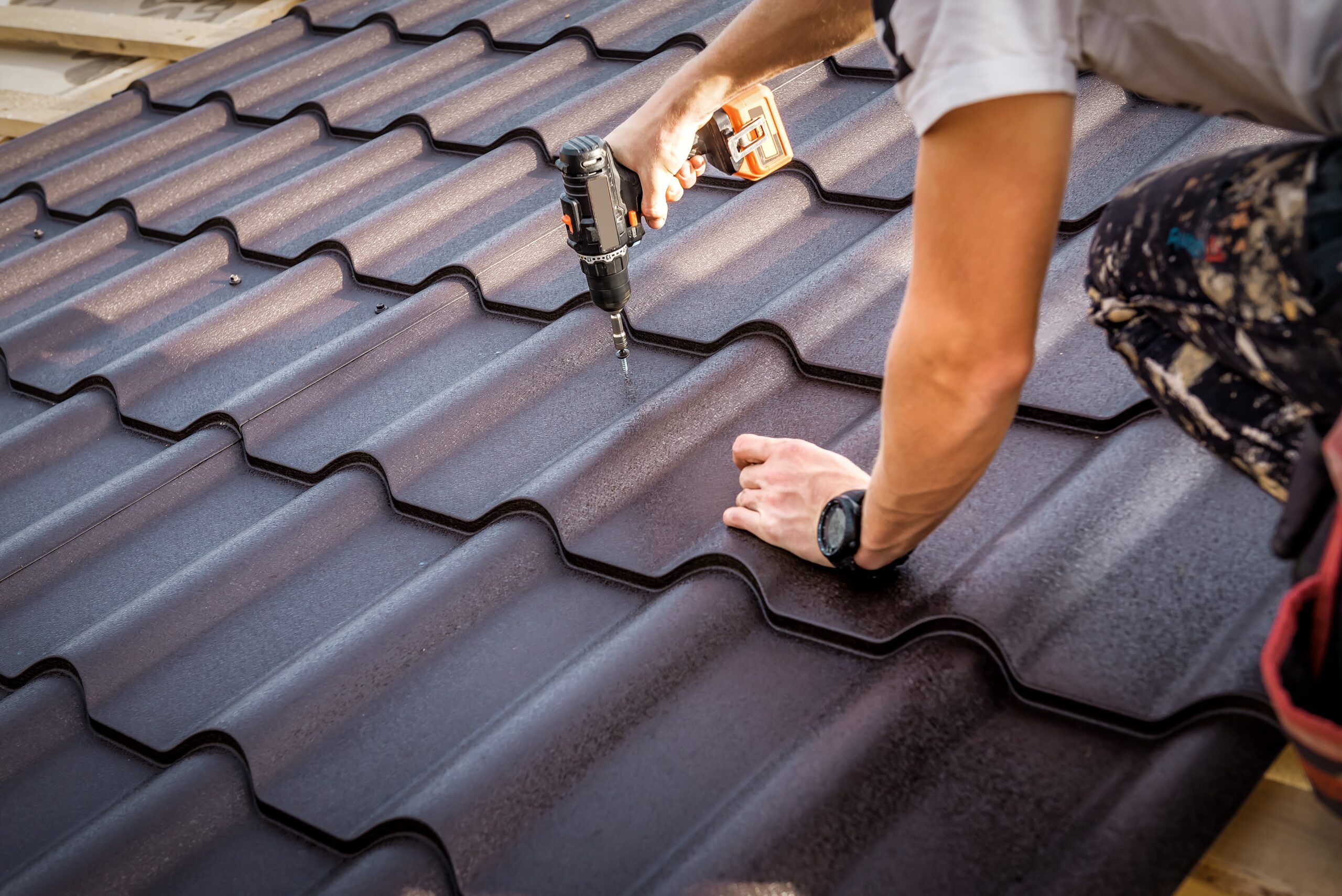 a person holding drilling machine and installing metal tiles