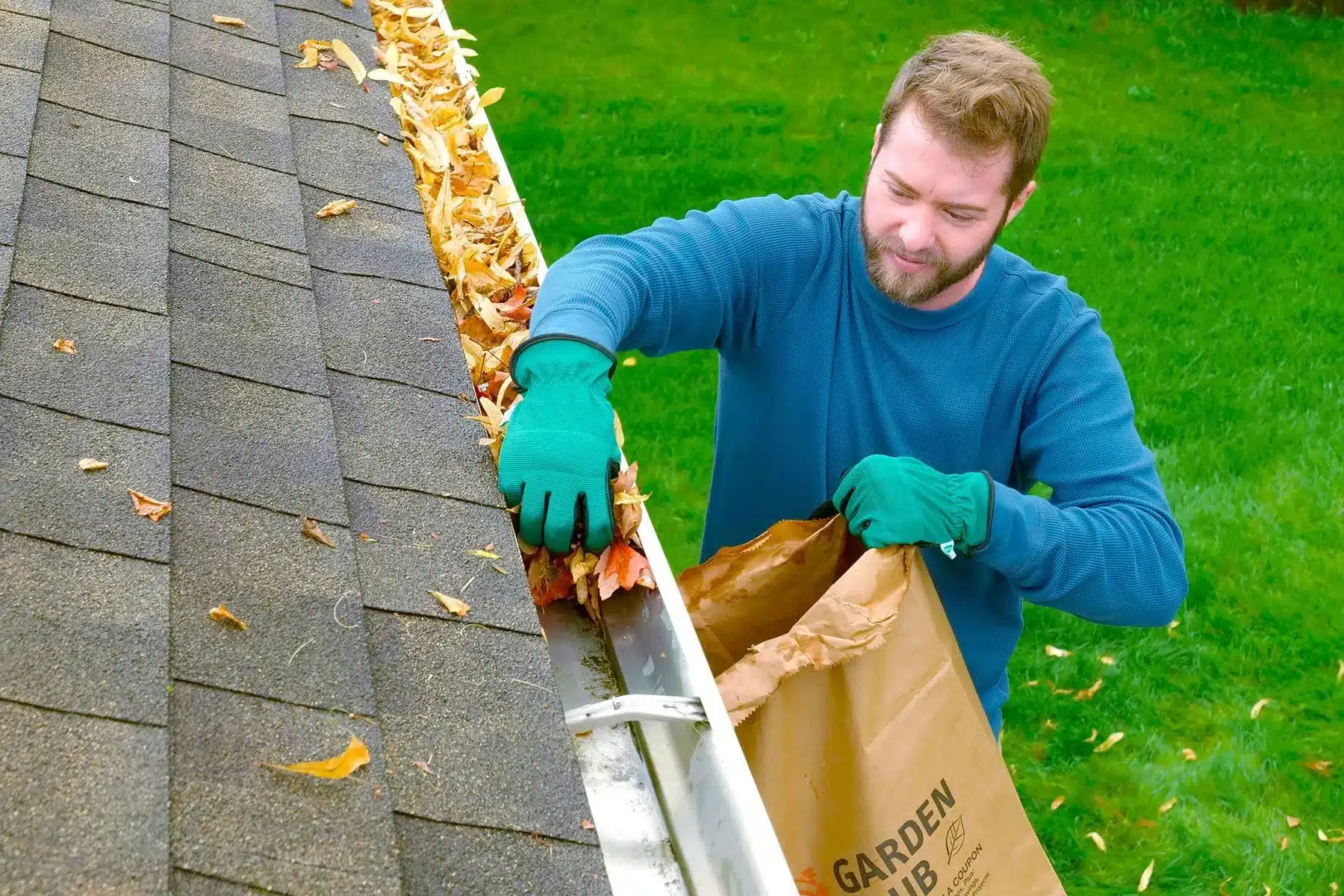 close up of a person cleaning roof gutter picking up leaves close up of a person cleaning roof gutter picking up leaves