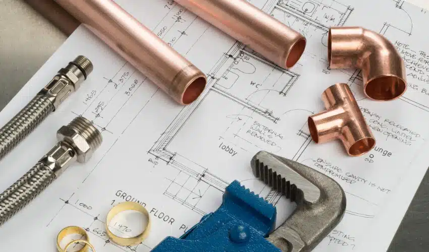 different plumbing tools placed on a paper with construction map different plumbing tools placed on a paper with construction map