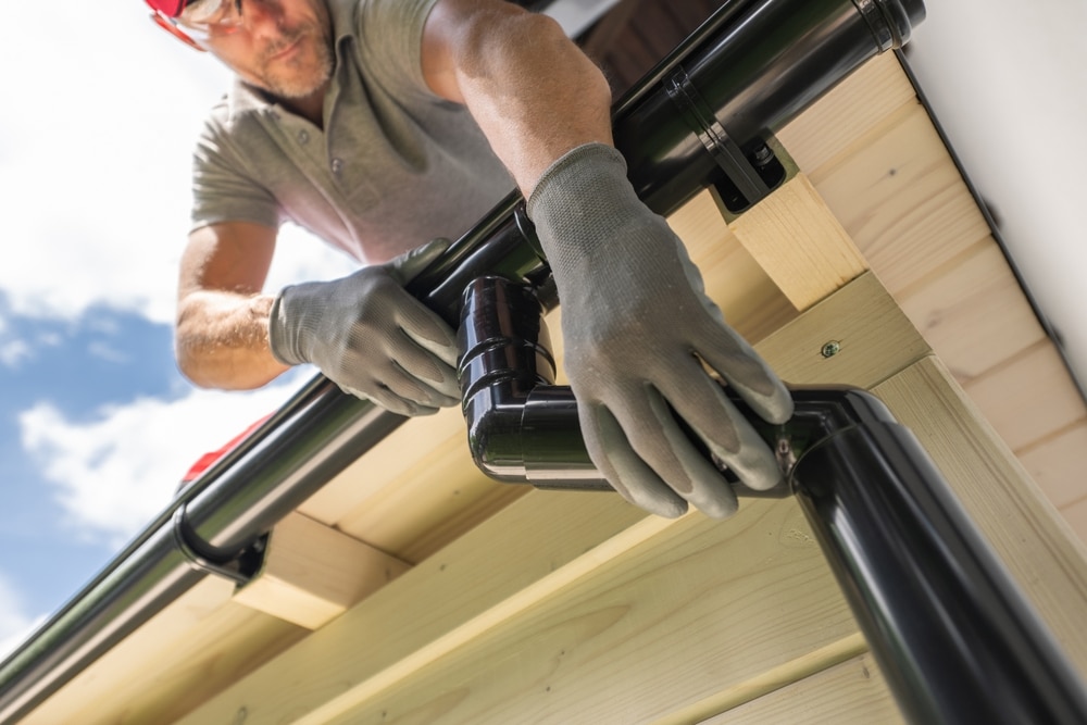 Worker Installing Gutter System On Roof Worker Installing Gutter System On Roof